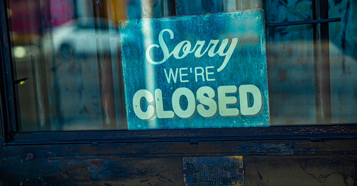 A closed sign hanging on the glass door of a small shop